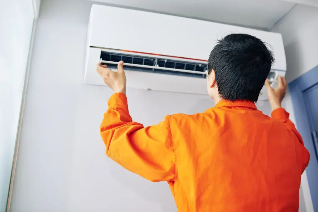 repairman orange uniform installing checking air conditioner apartment client